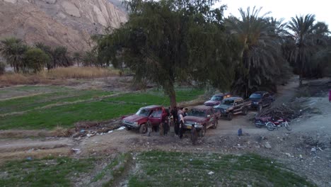 people-standing-under-tree-with-4x4-jeep-Aerial-Flying-Over-Remote-Road-Through-Mountainous-Valleys-In-Khuzdar