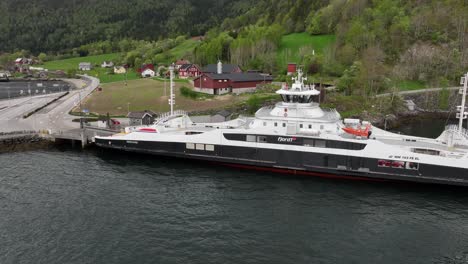 Antena-Alrededor-Del-Ferry-Eidsfjord-De-La-Compañía-Fjord-1-Mientras-Se-Encuentra-Junto-Al-Muelle-Del-Ferry-Lote-En-Nordfjord,-Noruega:-Antena-Que-Muestra-El-Ferry-Con-Batería-Eléctrica-Mientras-Se-Carga