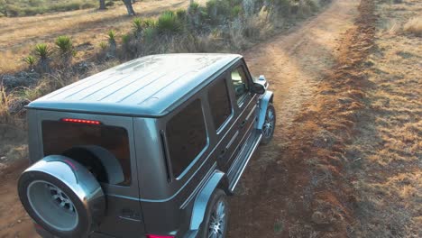 Luxurious-Mercedes-Benz-car-parked-in-middle-of-a-dirty-road-in-desert-at-sunset