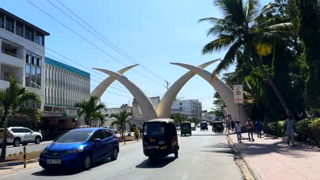 Cars-driving-through-Mombasa-city-in-Kenya-with-famous-Tusk-landmark
