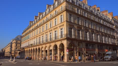 Atemberaubende-Und-Ikonische-Straßenlandschaft-In-Der-Rue-De-Rivoli,-Architekturgebäude-In-Der-Nähe-Des-Louvre-Mit-Menschen,-Die-Tagsüber-In-Paris,-Frankreich,-Einen-Rundgang-Machen