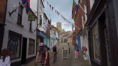 Cyclists-and-people-in-the-famous-and-historic-city-of-Lincoln,-Showing-medieval-streets-and-buildings