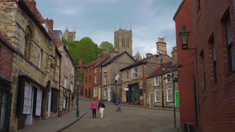 Tourists-walking-around-the-ancient-and-historic-city-of-Lincoln,-Showing-medieval-streets-and-buildings