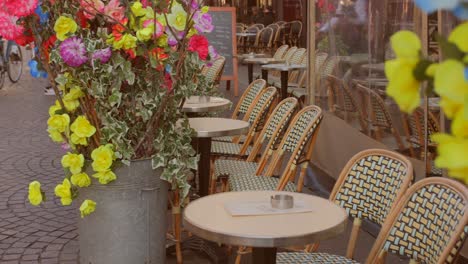 Leere-Reihe-Von-Stühlen-Und-Tischen-Mit-Bunten-Blumen-Auf-Der-Terrasse-Eines-Französischen-Restaurants-In-Paris,-Frankreich