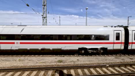 Side-POV-of-german-ice-train-passing-empty-rail-yard