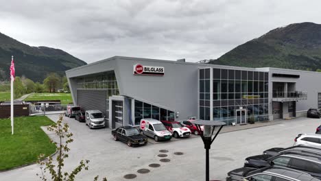RIIS-Bilglass-car-window-repair-and-shop-in-Forde-Norway---Exterior-view-with-logo-on-building-and-company-flag-waving-in-wind