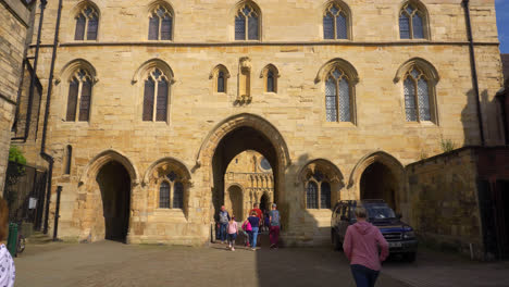 Tourists-at-Lincoln’s-unique-14th-century-Exchequergate-Arch,-which-frames-the-walkway-leading-to-the-West-Front-of-the-Cathedral