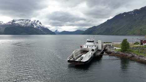 El-Ferry-Eléctrico-De-Cero-Emisiones-Eidsfjord-Está-Cargando-Baterías-Desde-El-Cargador-Del-Ferry-Mientras-Se-Encuentra-Junto-Al-Muelle-Del-Ferry-Lote-En-El-Oeste-De-Noruega---Ferry-Aéreo-Acercándose-Con-Un-Impresionante-Fondo-De-Fiordo