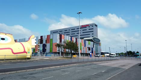 Panning-across-Yellow-submarine-and-Hilton-hotel-outside-John-Lennon-international-airport-glass-front-entrance,-England