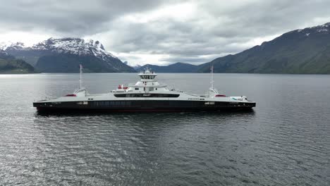 Ferry-Eléctrico-Gloppefjord-De-La-Compañía-Fjord1-Que-Cruza-Nordfjord-Entre-Anda-Y-Lote-En-El-Oeste-De-Noruega---Seguimiento-Aéreo-Del-Barco-Desde-El-Lado-Del-Mar-Con-Un-Hermoso-Paisaje-De-Fondo