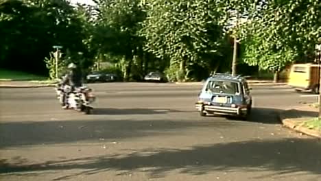 1980er-Jahre-Polizei-Motorrad-Biker-Polizist,-Der-In-Den-Verkehr-Fährt