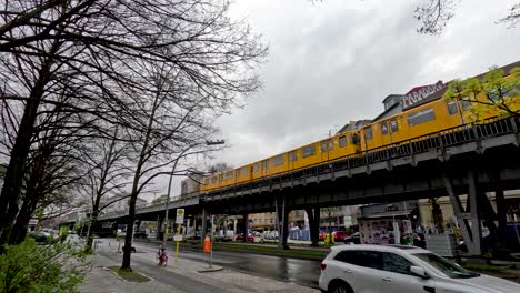 Gelbe-U-Bahn-Fährt-An-Einem-Bewölkten-Tag-In-Berlin-Auf-Hochbahn-In-Kreuzberg-Vorbei