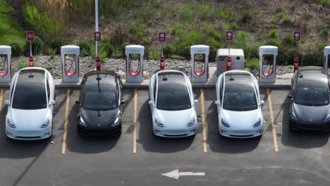 Luftaufnahme-Von-Tesla-Elektrofahrzeugen,-Die-An-Der-Supercharger-Station-Aufgeladen-Werden