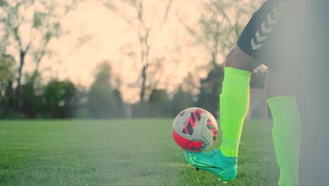 Soccer-player-doing-kick-ups-on-soccer-field-at-sunset
