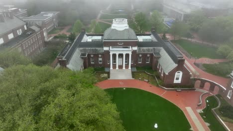 Rotational-aerial-shot-of-historical-academic-architecture-on-foggy-college-campus