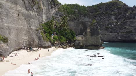 Antena,-Turistas-Relajándose,-Tomando-El-Sol-Y-Nadando-En-La-Playa-De-Diamantes-En-La-Isla-De-Nusa-Penida,-Bali---Indonesia