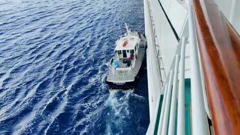 Ein-Lotsenboot-Aus-Cozumel-Manövriert-Elegant-Durch-Das-Wasser,-Das-Zu-Betriebszwecken-An-Der-Seite-Eines-Kreuzfahrtschiffes-Befestigt-Ist-|-Reibungslose-Und-Sichere-Navigation,-Wenn-Sich-Das-Kreuzfahrtschiff-Seinem-Ziel-Nähert