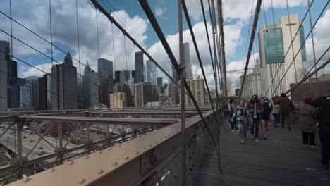 Menschen,-Die-Den-Gehweg-Auf-Der-Brooklyn-Bridge-Entlang-Gehen-Und-Die-Skyline-Von-Manhattan-Durch-Drähte-Sehen