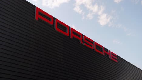 Against-the-backdrop-of-the-sky-stands-a-tall-black-building-with-the-Porsche-company-logo-displayed-prominently