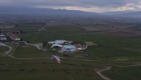 Drone-follows-paragliders-descent-over-Turkish-landscape-morning-dim-light