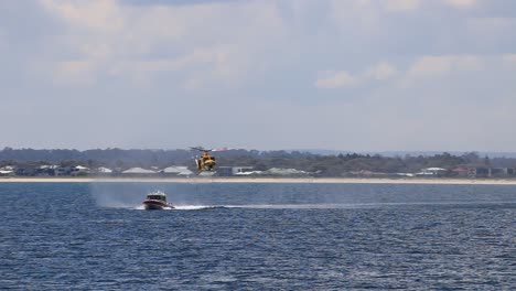 Helicóptero-De-Rescate-Perth-Rac-Persiguiendo-Un-Bote-De-Rescate-Marino-Y-Bajando-El-Cable-Del-Cabrestante,-Visto-Desde-El-Embarcadero-De-Busselton