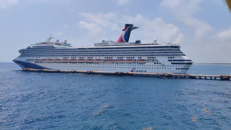 A-Carnival-ship-gracefully-maneuvers-in-reverse,-inching-closer-to-the-dock-on-a-bustling-port,-ready-to-dock-and-embark-on-its-next-adventure-|-Vacation,-tourism,-lifestyle,-cruising-concept