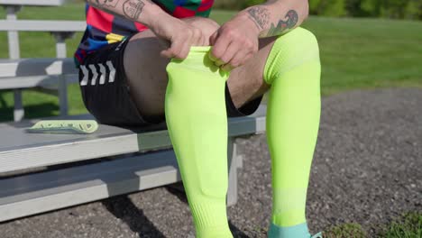 Soccer-player-putting-on-shin-guards,-preparing-to-play