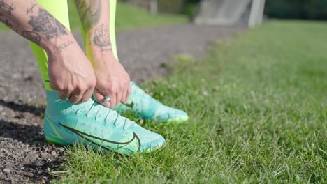 Close-up-of-soccer-player-tying-sneakers-on-soccer-field-bench
