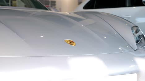 In-the-car-showroom,-there-is-a-white-Porsche-standing-upfront,-captured-up-close
