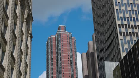 Looking-Up-At-Red-High-Rise-Residential-Apartment-Block-In-New-York-Against-Blue-Skies-And-Light-Clouds
