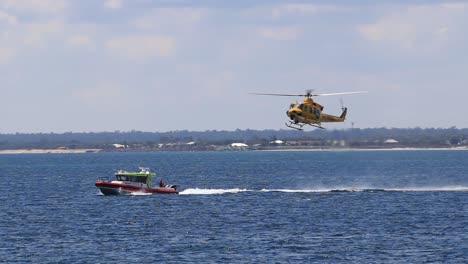 Rescue-Helicopter-Descending-And-Lowering-Winch-Cable-Onto-Moving-Coastguard-Boat,-Busselton