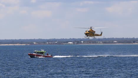 Helicóptero-De-Rescate-Descendiendo-Y-Bajando-El-Cable-Del-Cabrestante-En-Barco-Guardacostas-En-Movimiento,-Busselton