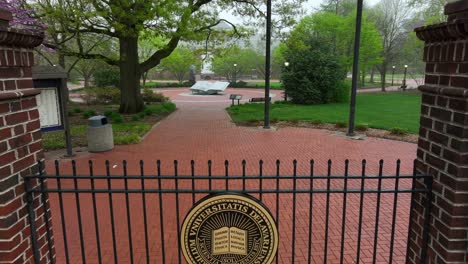 Rising-aerial-shot-of-University-of-Delaware-crest-on-gate-in-front-of-campus-monument