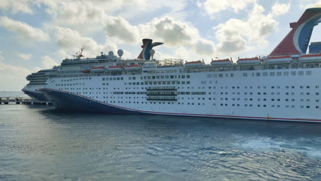 Ein-Luxus-Kreuzfahrtschiff-Karneval,-Das-Paradise-Bewegt-Sich-Im-Hafen-Rückwärts-Und-Enthüllt-Ein-Weiteres-Am-Hafen-Angedocktes-Kreuzfahrtschiff,-Videohintergrund-In-4K-|-Karnevalskreuzfahrtschiff,-Das-Anmutig-Vom-Hafen-Wegfährt