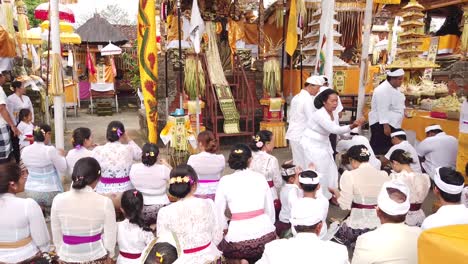 Die-Verehrte-Priesterin-Segnet-Gläubige-Bei-Der-Zeremonie-Im-Balinesischen-Hindu-Tempel,-Farbenfrohe-Ornamente-Werden-Ausgestellt