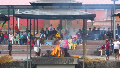 Un-Hombre-Avivando-El-Fuego-De-Cremación-En-El-Templo-De-Pashupatinath-En-Katmandú.
