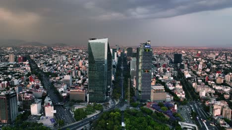 Aerial-view-away-form-downtown-skyscrapers,-sunny-evening-in-Mexico-city---pull-back,-drone-shot