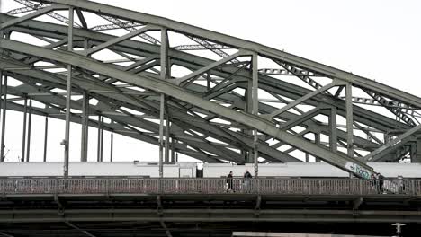 Vista-Desde-El-Paseo-Del-Rin-Del-Puente-Hohenzollern-Con-El-Tren-De-Alta-Velocidad-Deutsche-Bahn-Y-Gente-Pasando