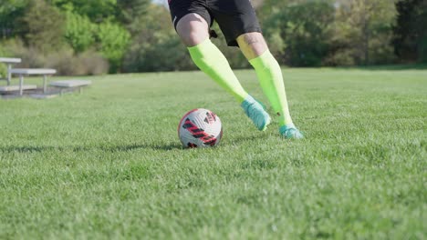 Soccer-player-practicing-step-over-on-lawn-in-sunny-day