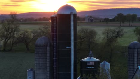 Aerial-establishing-shot-of-rural-farm-with-silos-in-USA-during-spring-sunset
