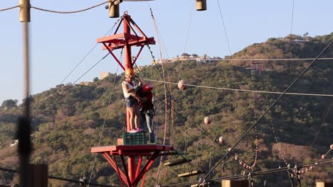 Instructor-attaching-equipment-to-a-woman-about-to-jump-on-a-zip-line