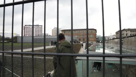 Visitor-Seen-Walking-Past-Wire-Fence-At-Topography-of-Terror-In-Berlin