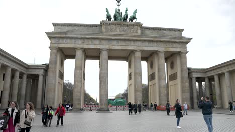 Zeitlupenaufnahme-Des-Brandenburger-Tors-Mit-Touristen,-Die-Abends-Im-Vordergrund-In-Berlin,-Deutschland,-Spazieren-Gehen