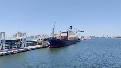 Ein-Riesiger-Kran-Dominiert-Den-Hafen,-Während-Er-Container-Von-Einem-Riesigen-Frachtschiff-Entlädt