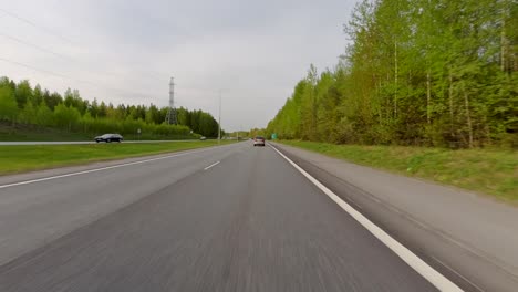 Autos-Navigieren-Unter-Dem-Tageshimmel-Anmutig-über-Die-Straße,-Die-Auf-Beiden-Seiten-Von-Einem-Kiefernwald-Begrenzt-Wird