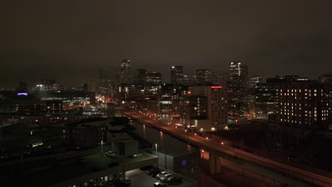 Aerial-reveal-of-night-view-of-Denver,-Colorado-skyline-from-behind-apartment-building