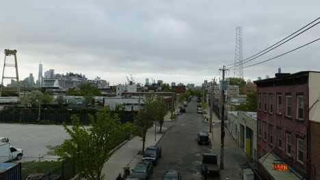 Aerial-view-rising-up-from-the-streets,-revealing-the-Red-Hook-Brooklyn-cityscape-and-the-gloomy-NYC-skyline