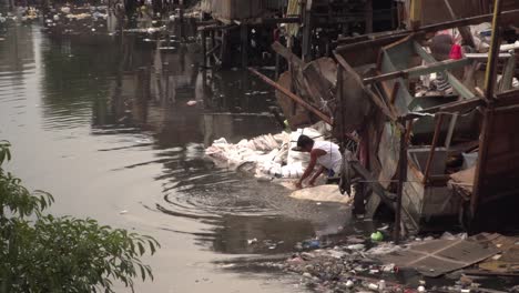 Vergrößern-Sie-Einen-Mann,-Der-In-Einem-Schmutzigen-Fluss-In-Einem-Slumgebiet-In-Manila-Wäsche-Wäscht