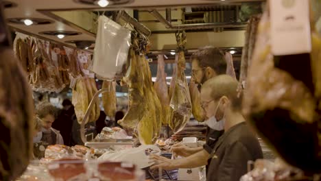 Verkäufer-Einer-Metzgerei,-Die-Abends-Im-Mercado-De-La-Boqueria-In-Barcelona,-Spanien,-Lebensmittel-Und-Produkte-Bezahlen