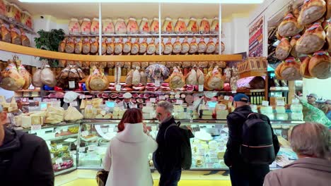 Varios-Clientes-Comprando-Jamón-En-Una-Tienda-De-Delicatessen-Local-En-Italia